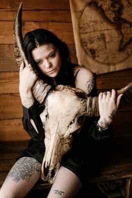 wistful young lady in mini skirt embracing steer skull